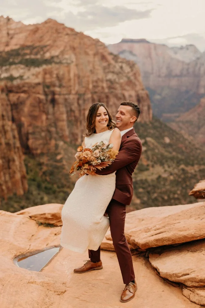 A groom holding his bride at a vista viewpoint in Zion.
