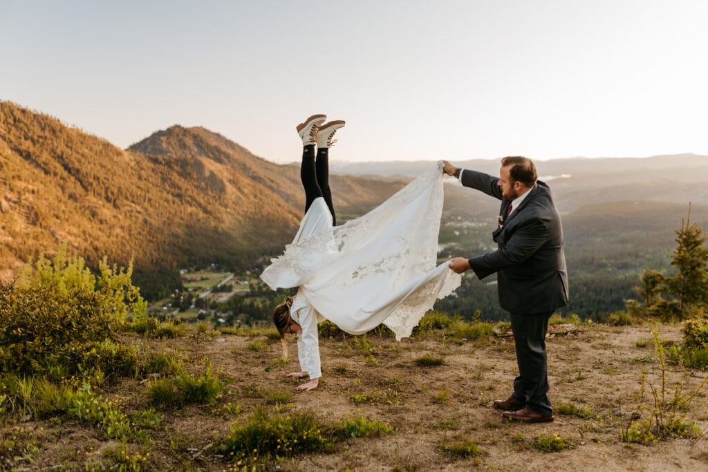 A bride does a hand stand in her wedding dress.
