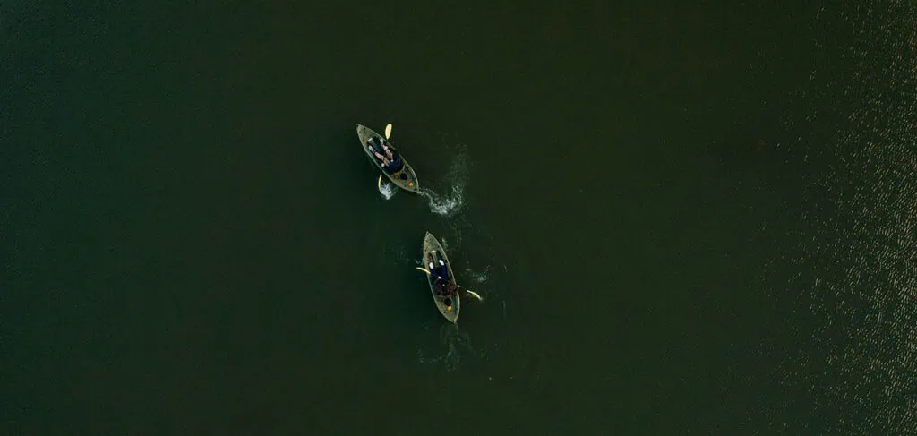 A drone photograph of a bride and groom kayaking together.