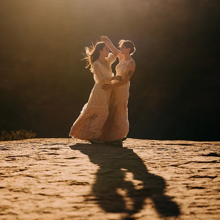 Two brides dance in the sunlight among the red rocks.