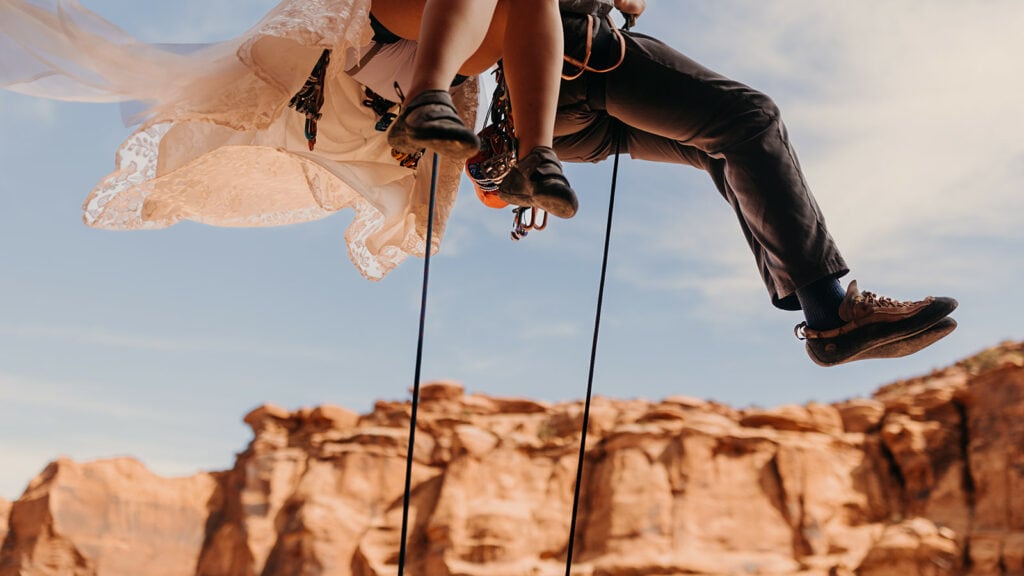A detail photo of a couple rock climbing together on their wedding day.