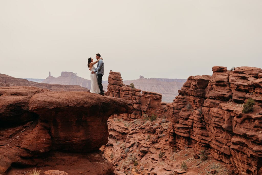The couple stands for a portrait on a rock.
