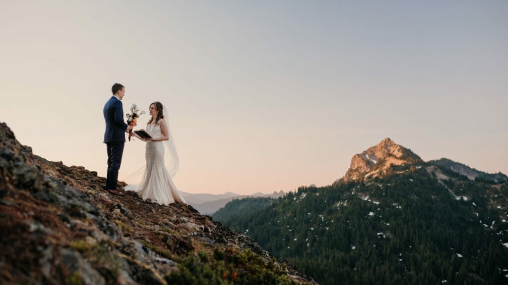 A couple shares vows at sunrise on top of a mountain.