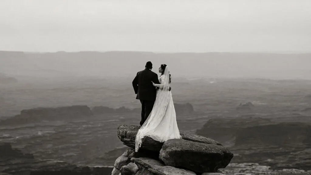 The couple holds each other and looks out at the view.