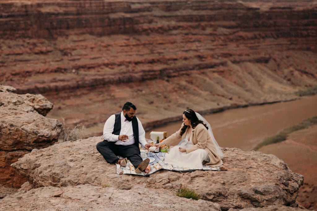 The couple sits to have a picnic in Moab.