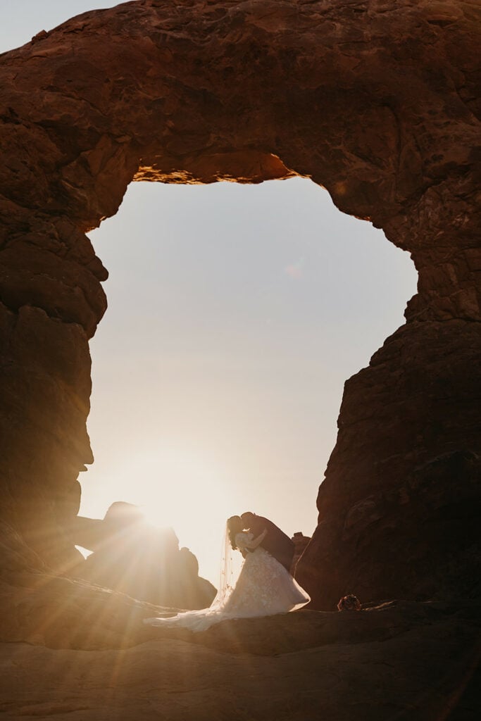 a bride and groom share a kiss under turret arch in arches national park