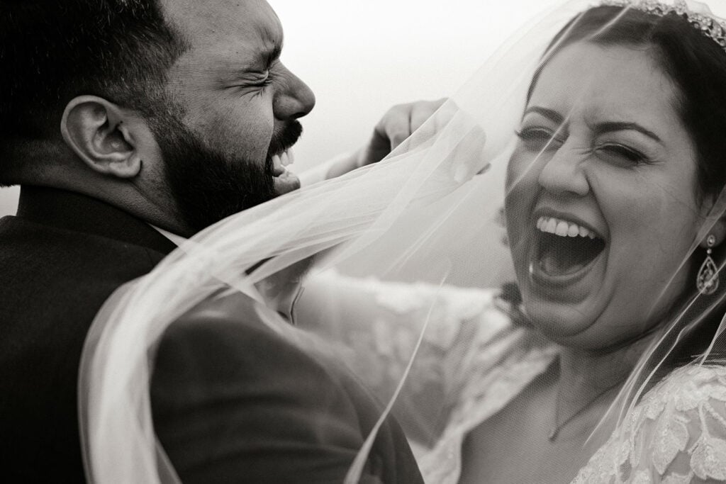 The bride laughs as her veil blows in the wind.
