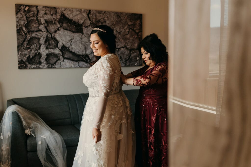 The bride's mother helps her into her dress.