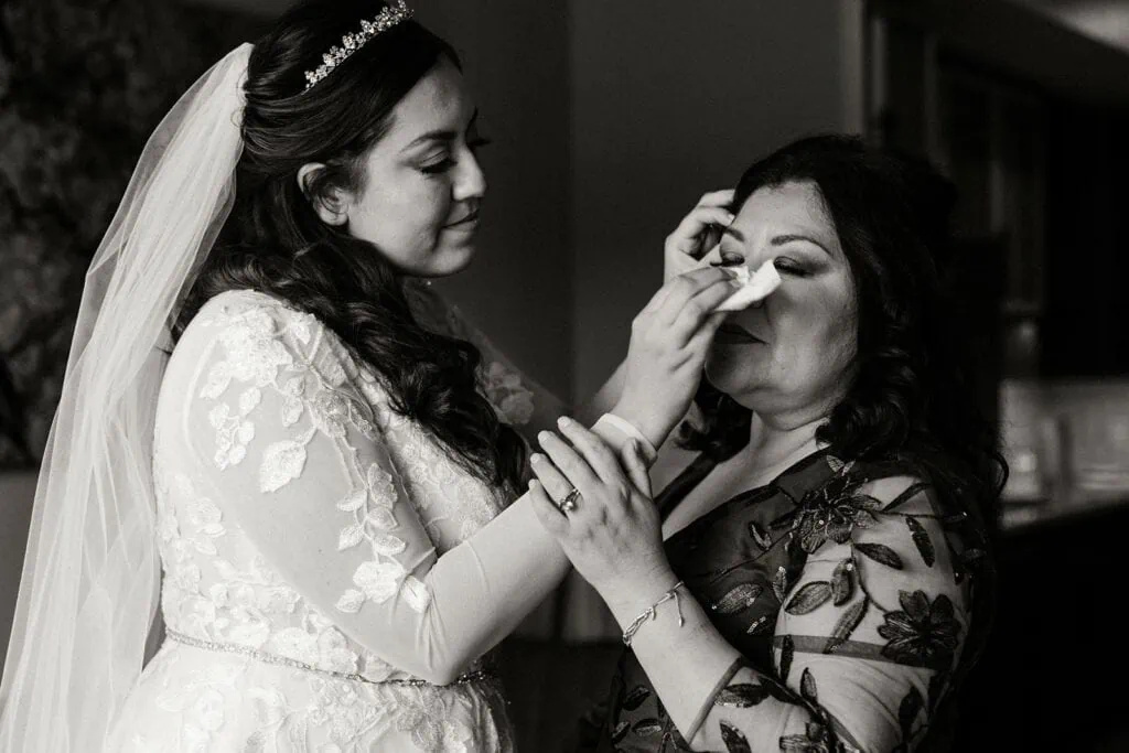 The bride wipes her mom's tears.
