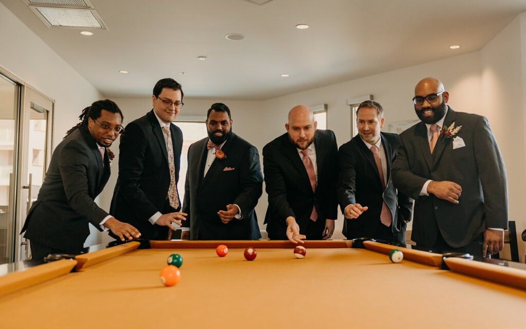 The groom and his friends play pool.