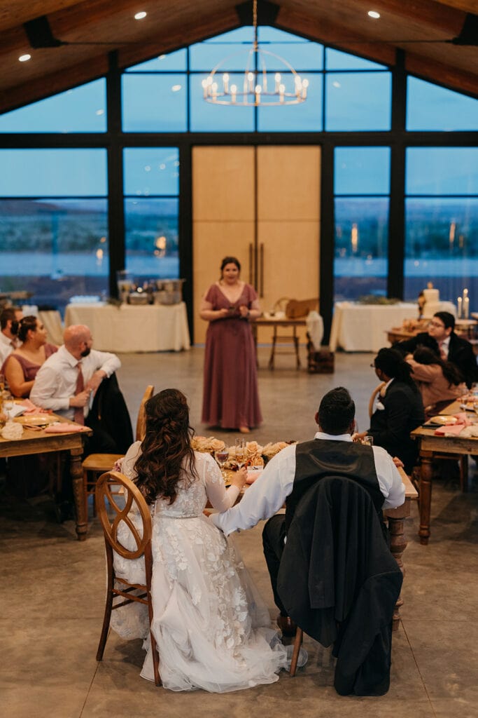 The maid of honor gives a toast to the couple inside the glass house at red earth venue.