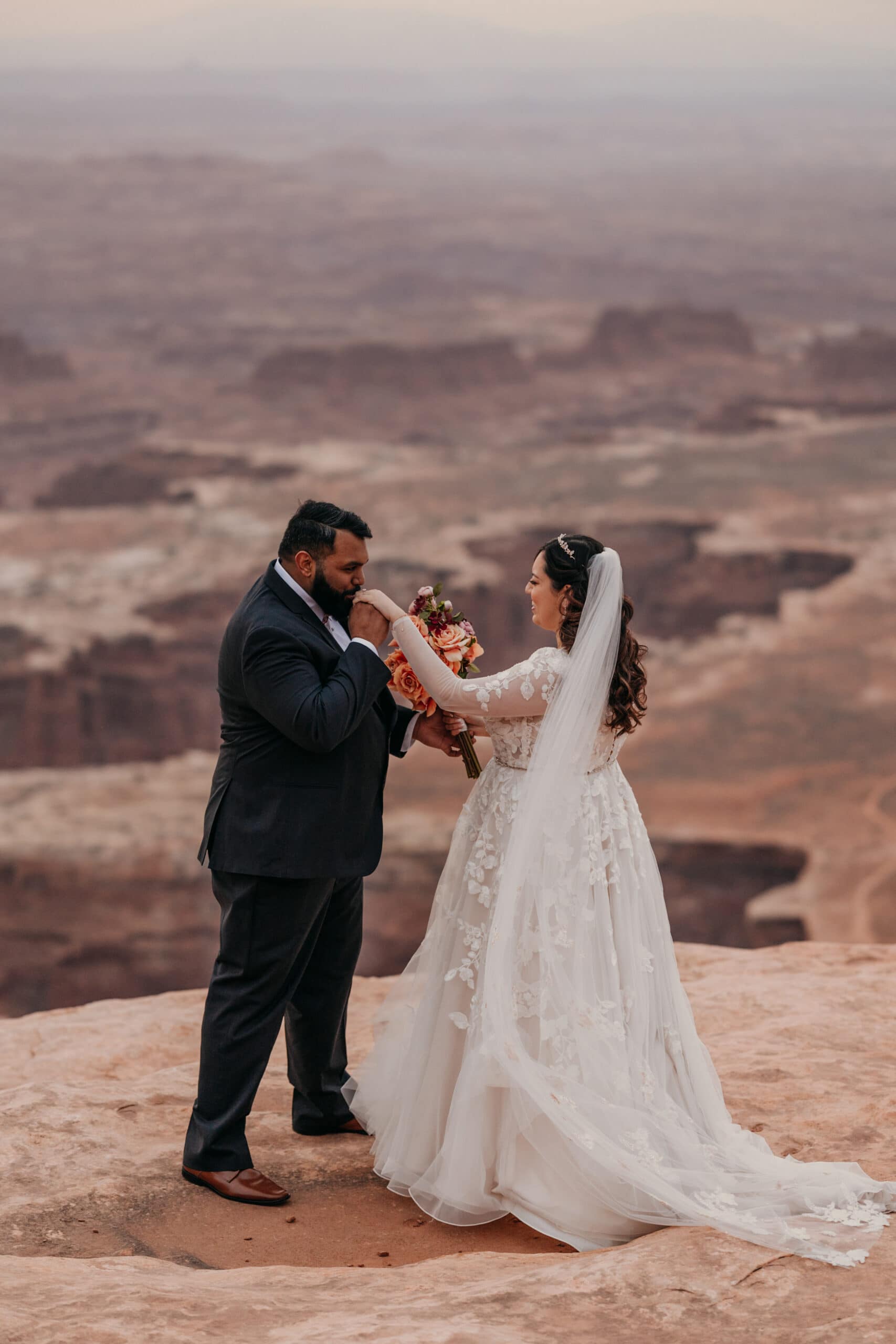 A groom kisses the hand of his bride at their first look in Canyonlands.