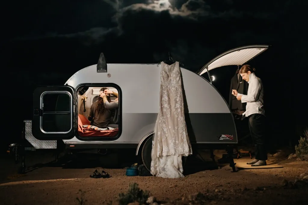The groom gets ready outside of the RV while the bride gets ready inside the RV and her dress hangs outside.