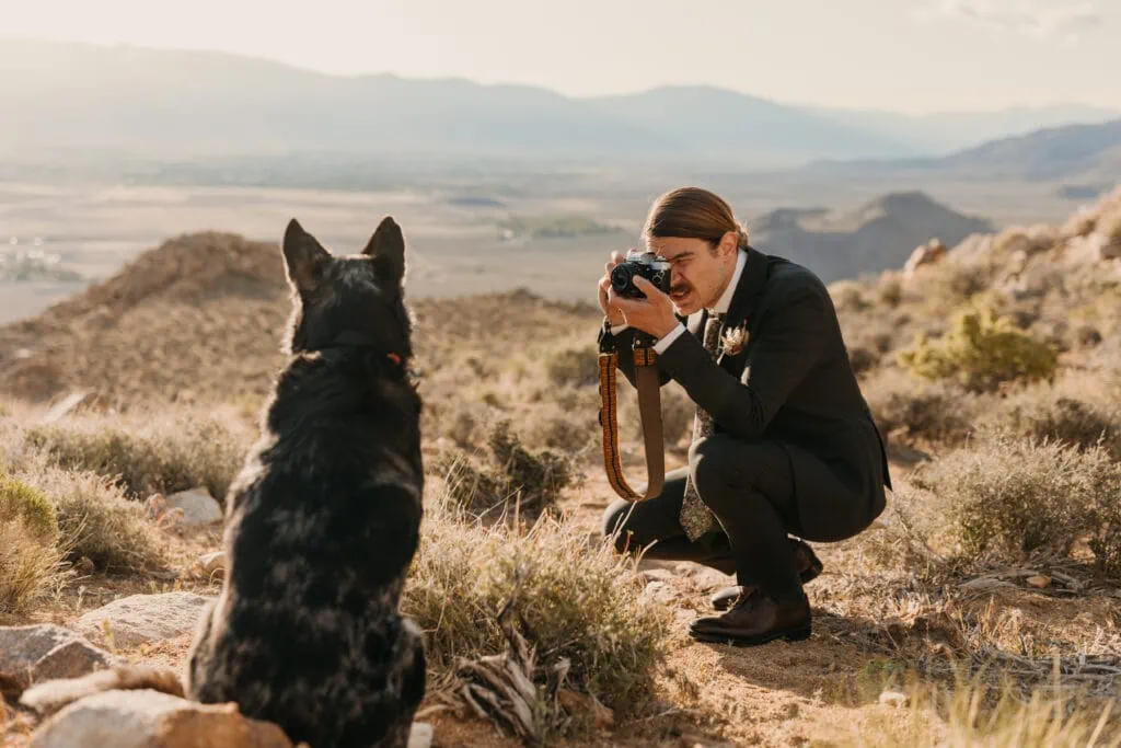 The groom takes a photo of his dog on a film camera. 