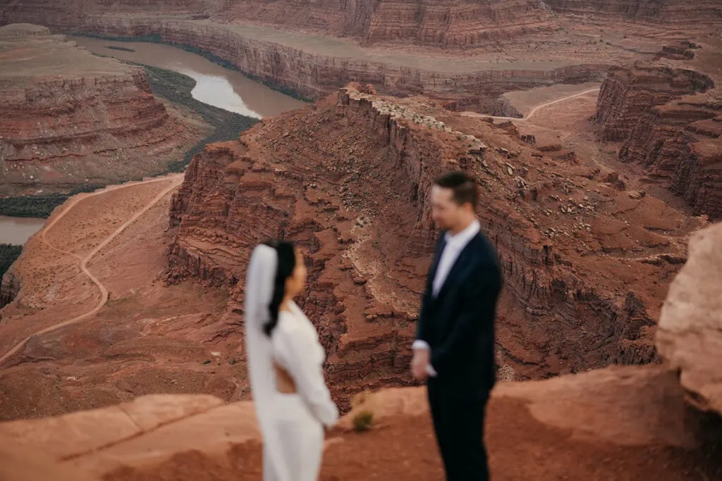 A bride and groom stand together at Dead Horse Point at Sunset