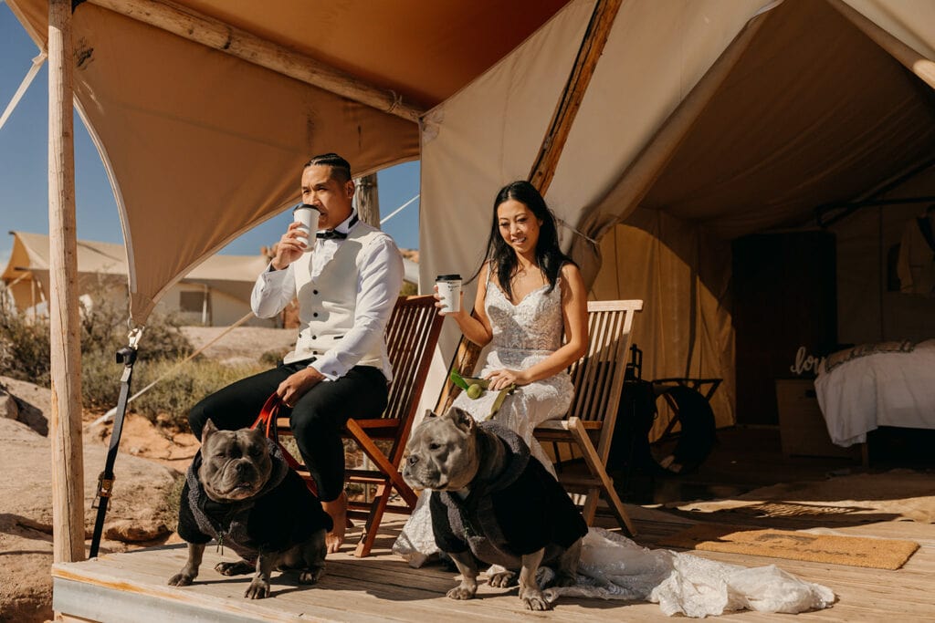 The bride and groom share coffee on the porch with their dogs.