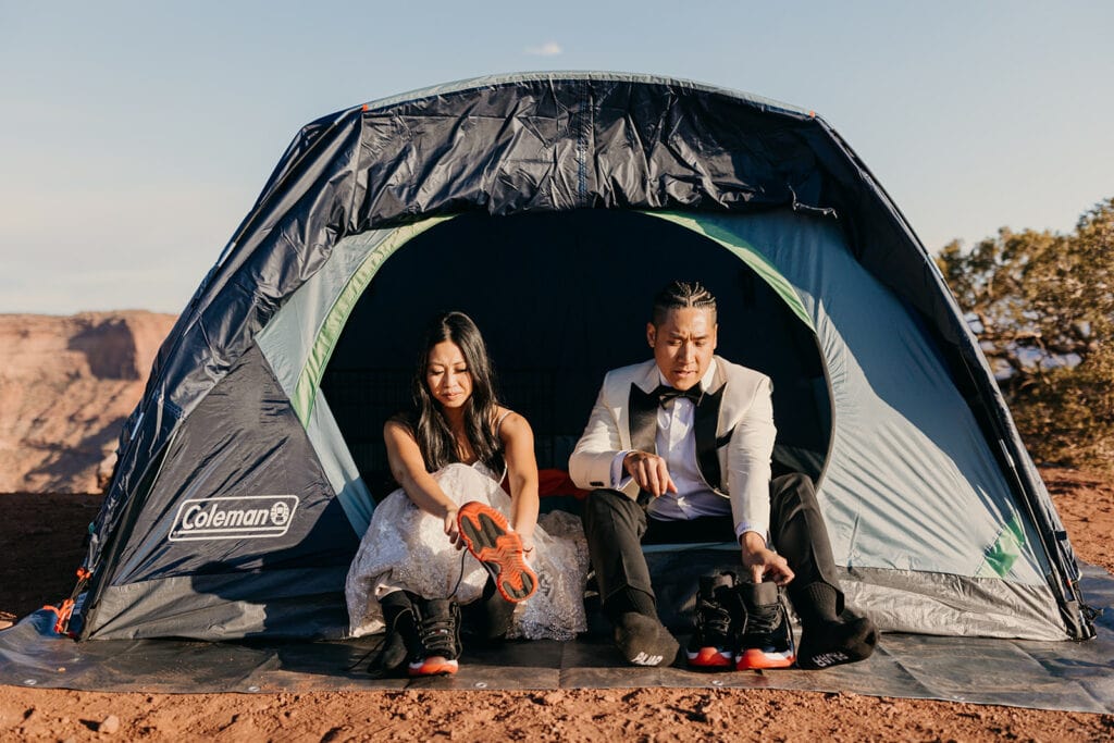 The couple sits in their tent to put their shoes on together.