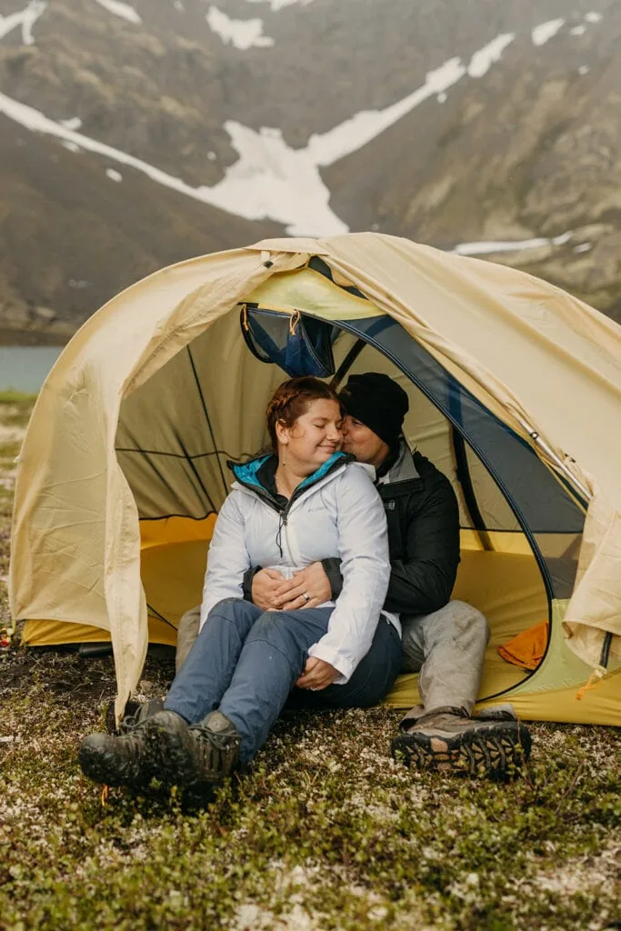 The couple snuggles up in the tent.