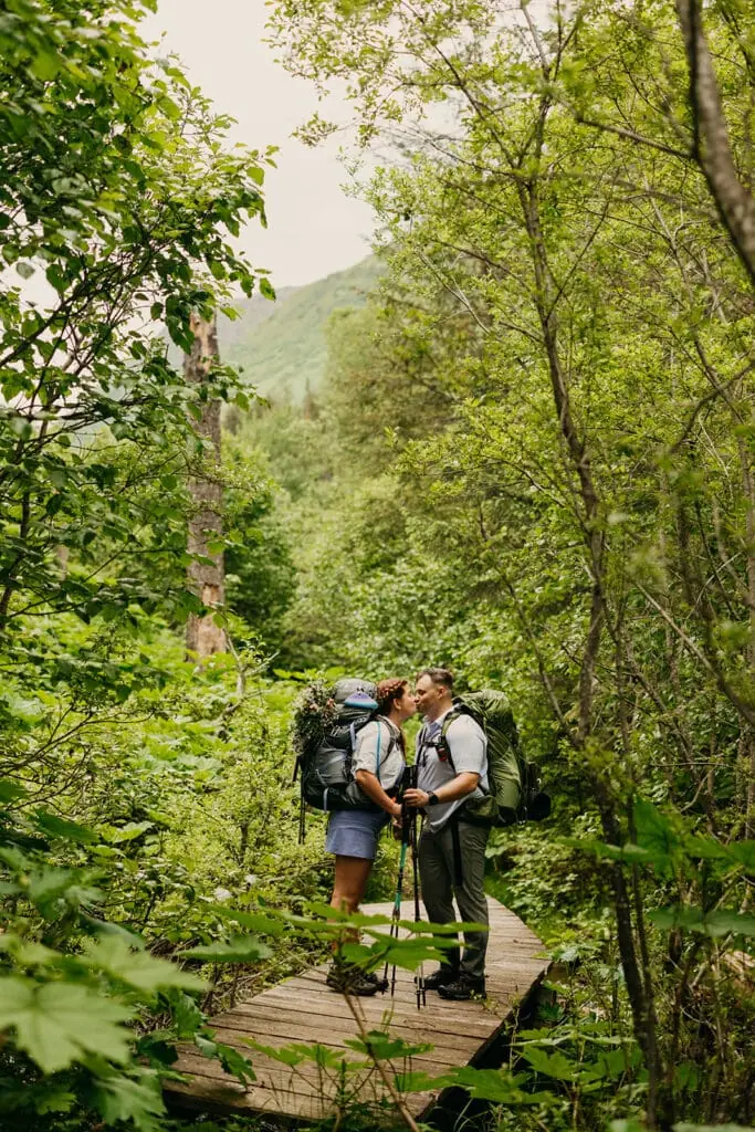 A couple shares a kiss on a bridge while backpacking.