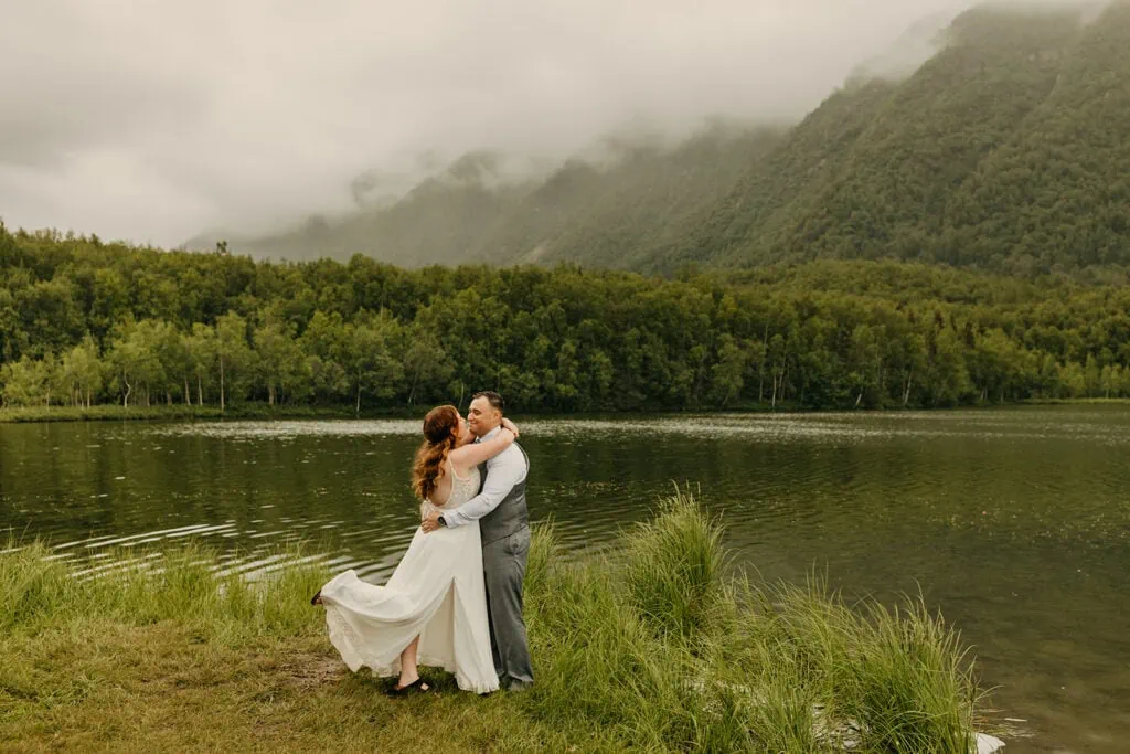 THe couple poses for a photo by a lake.