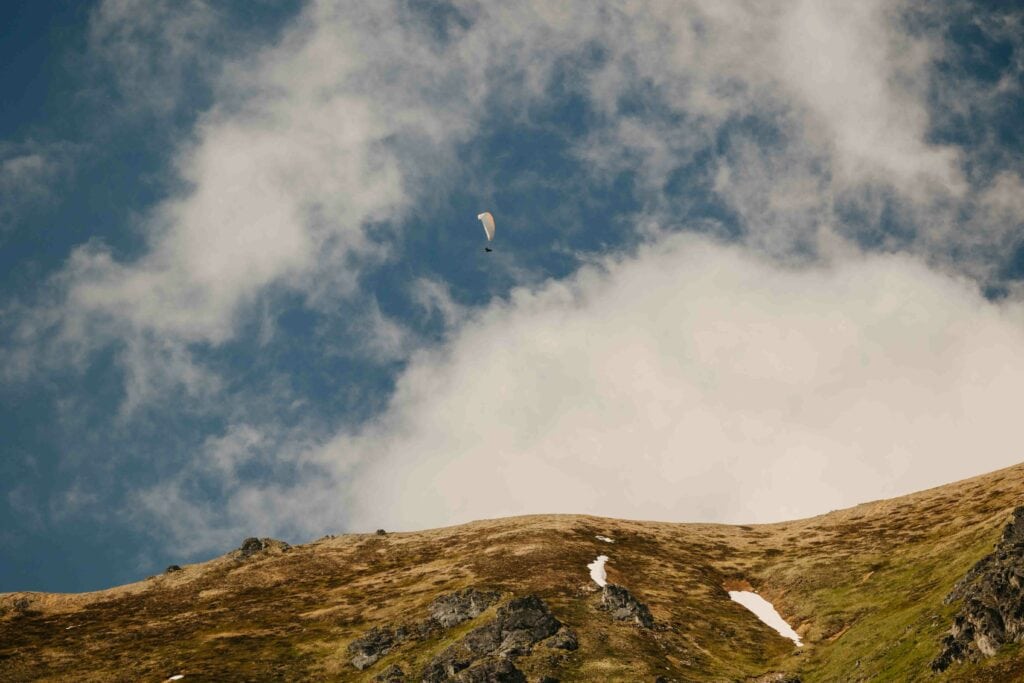 A person parasails at Hatcher Pass on a partly cloudy day in alaska.