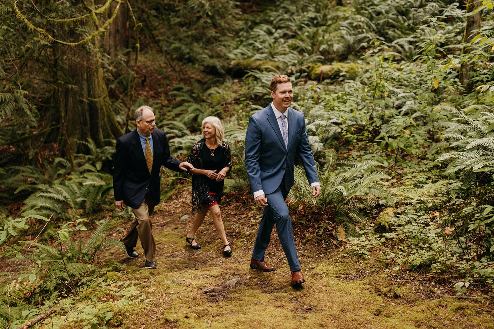 The groom hikes down the aisle with his parents.