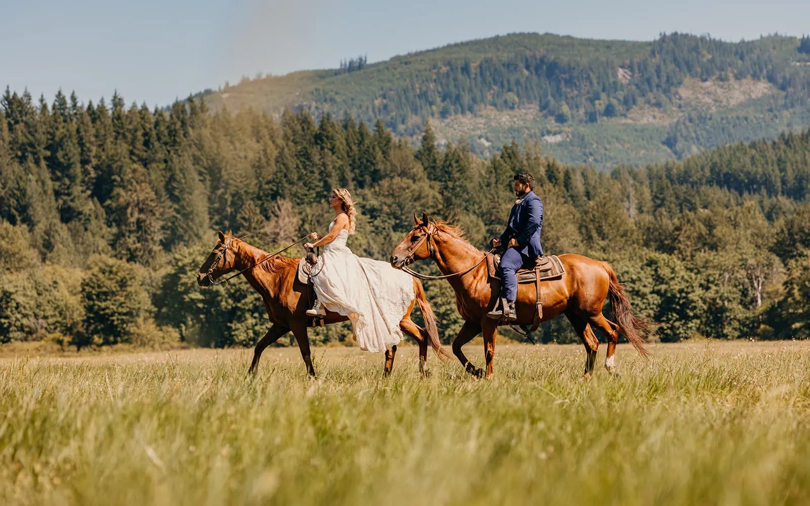 A bride and groom ride horseback mid day on their wedding day.