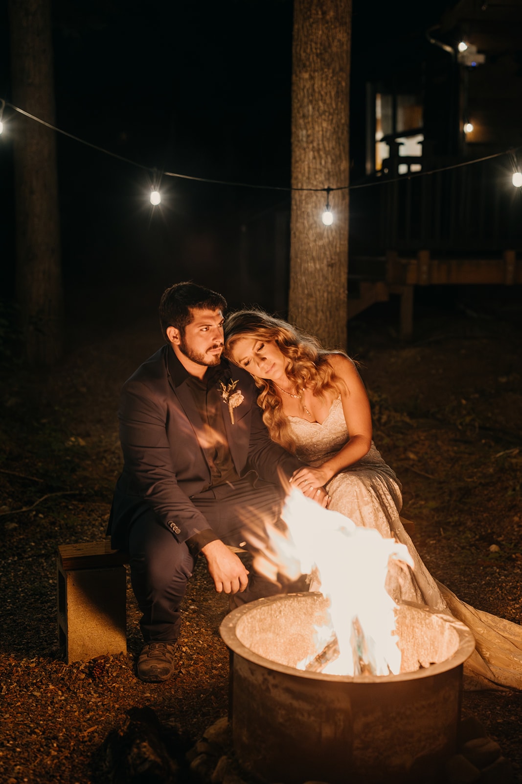 The couple sits by a fire together.