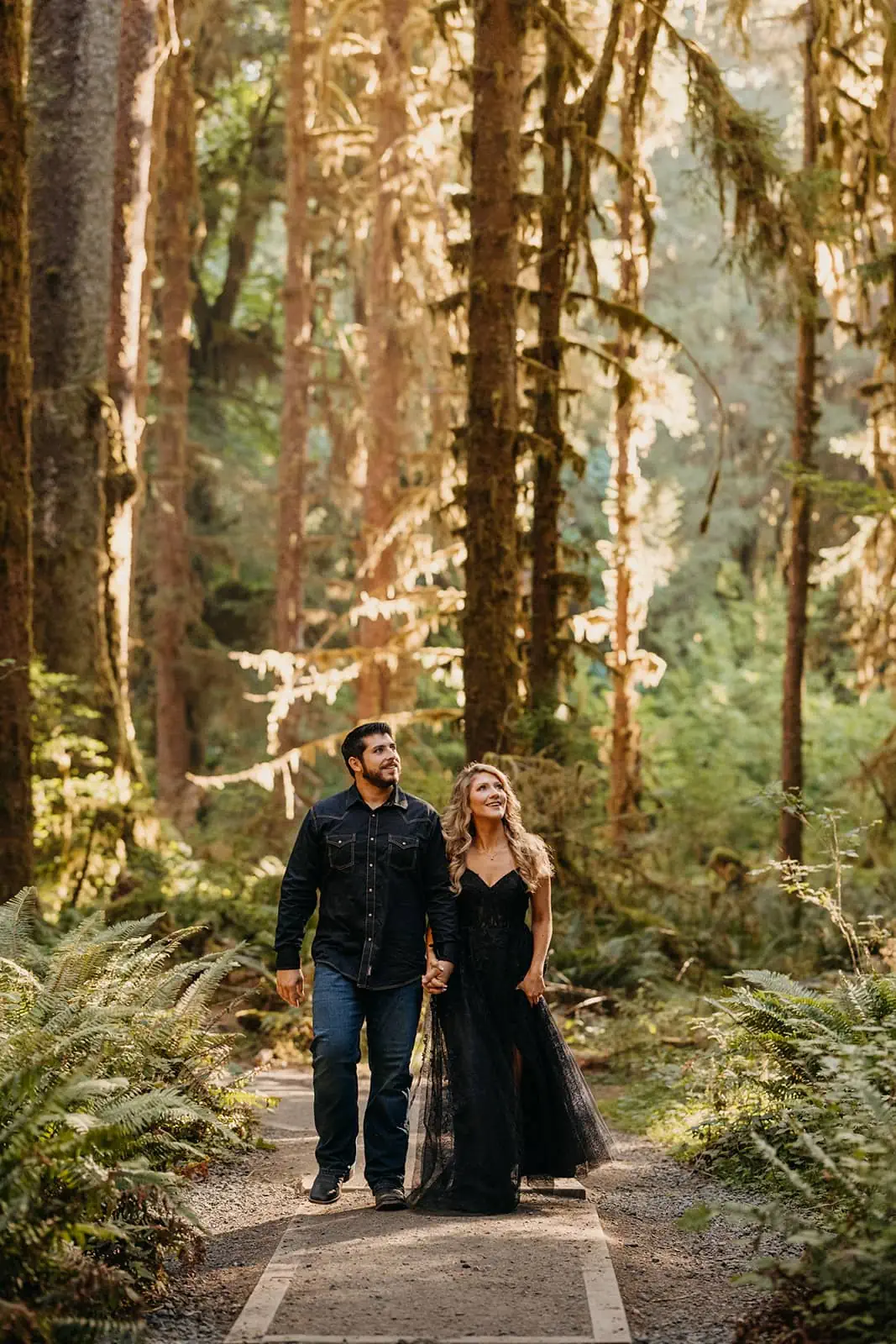 A couple walks together admiring the moss and massive trees in the HOH Raineforest.