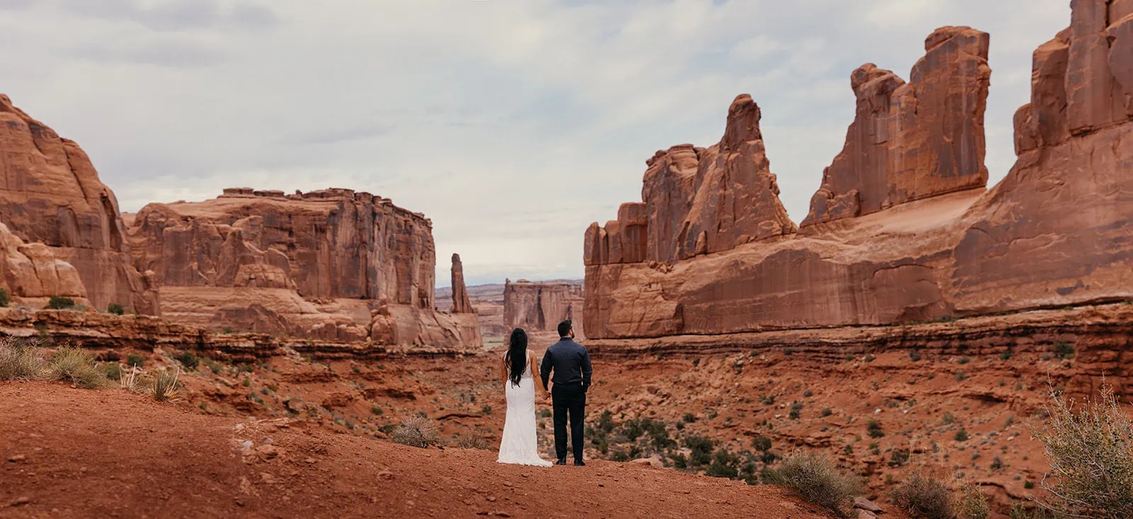 A couple stands for a portrait in Arches National Park.