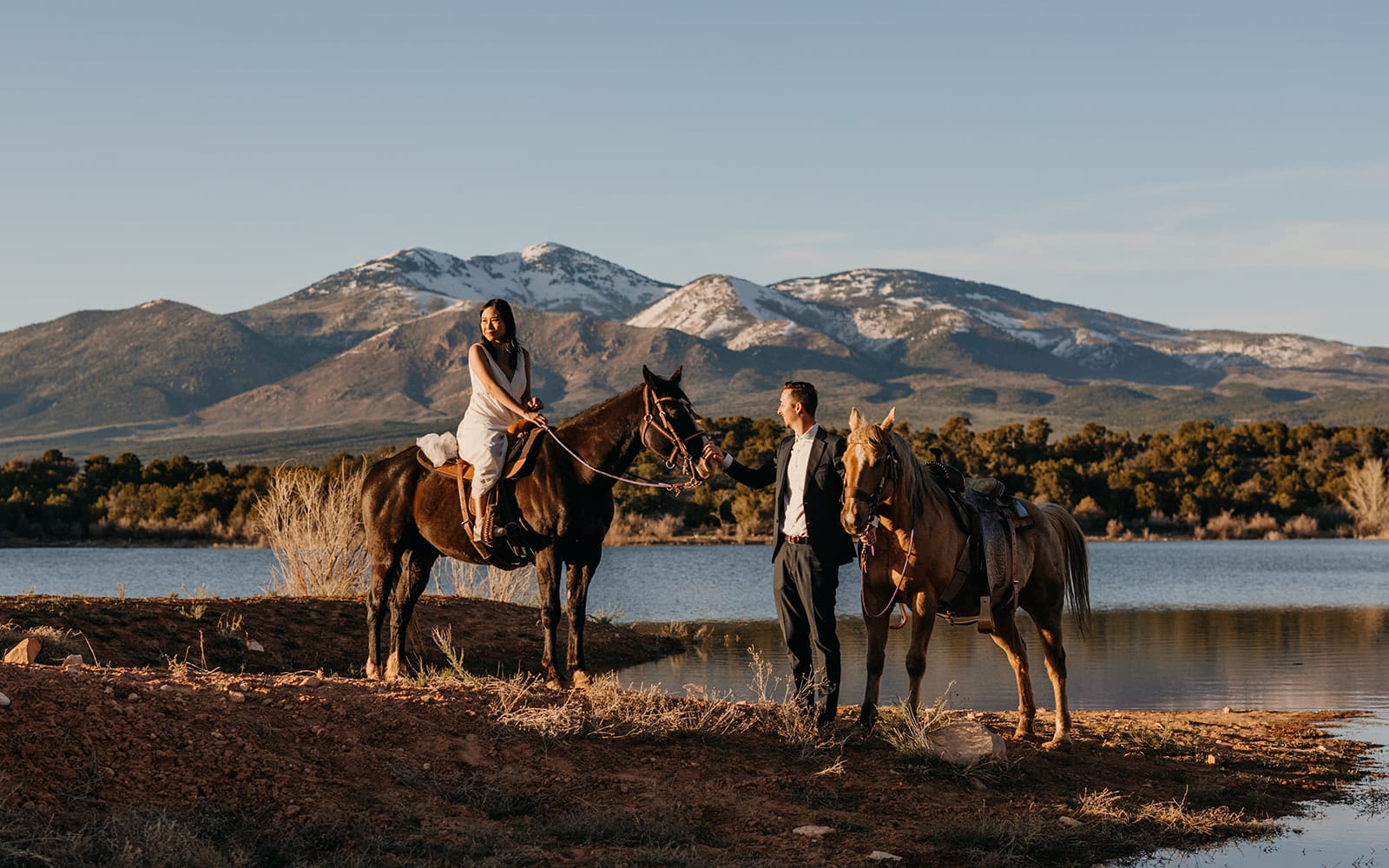 A couple rides horses overlooking the La Sal Mountain Range in Moab.