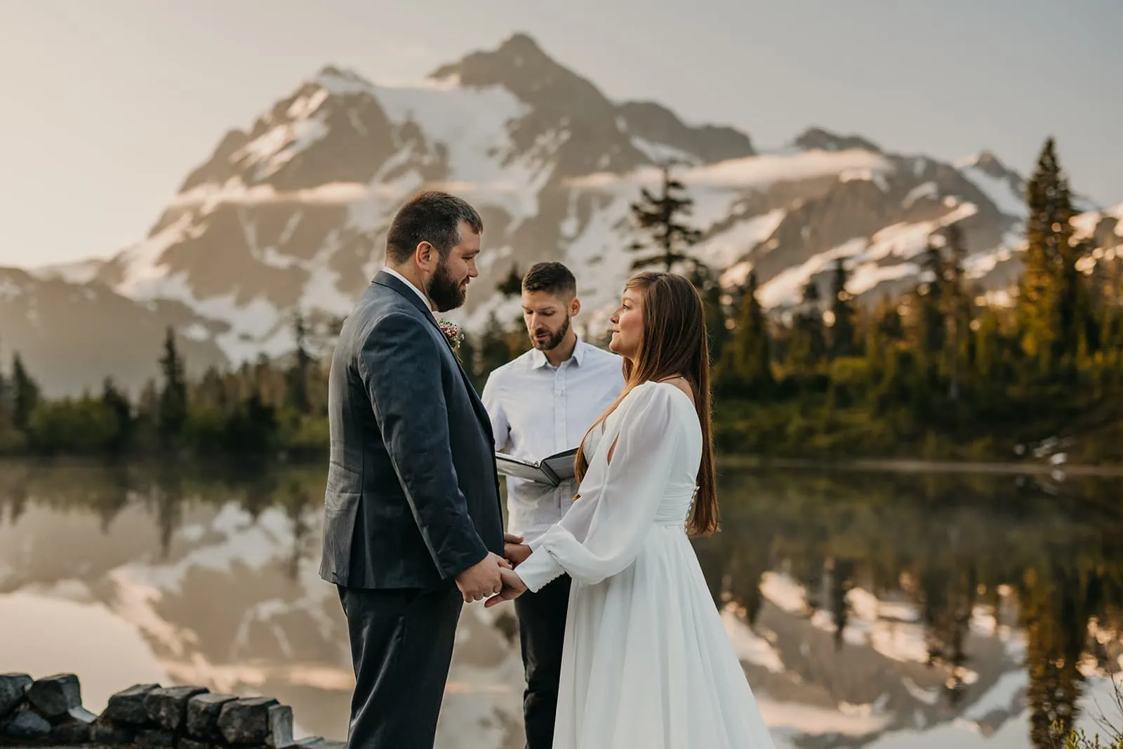 A couple holds their elopement ceremony at Picture Lake at sunrise. 