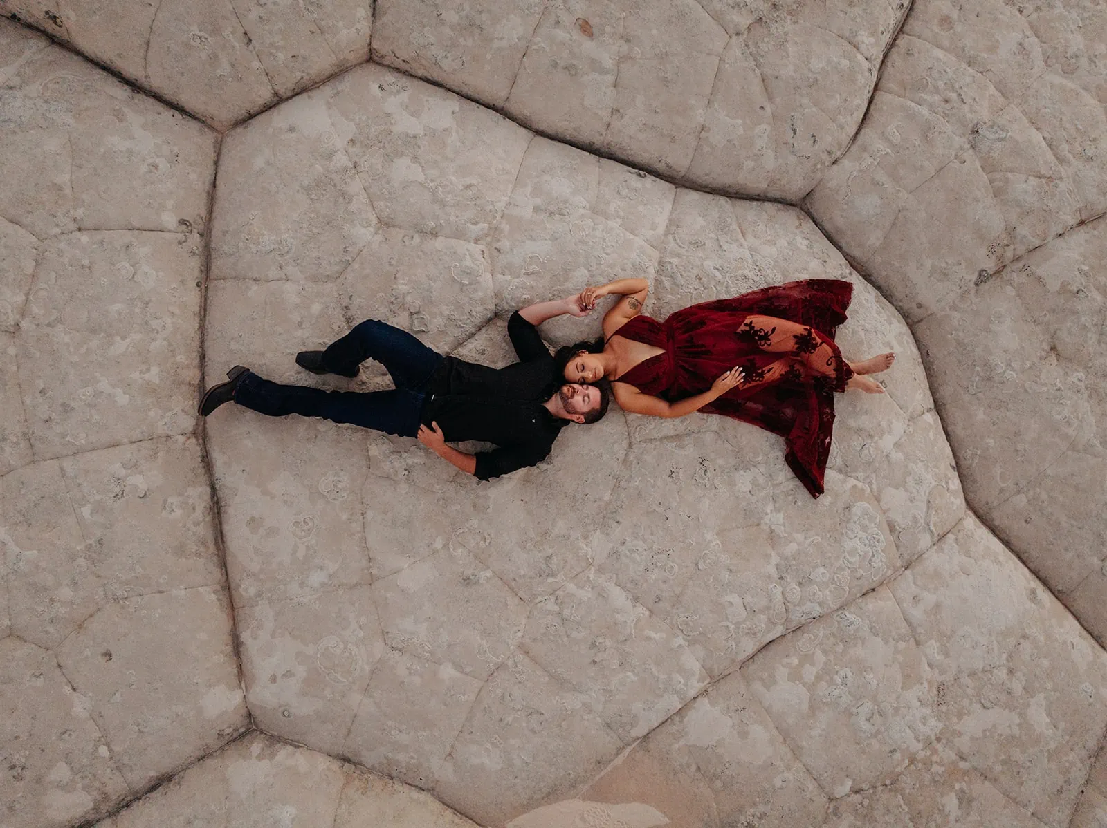 A bride and groom lay together in the desert.