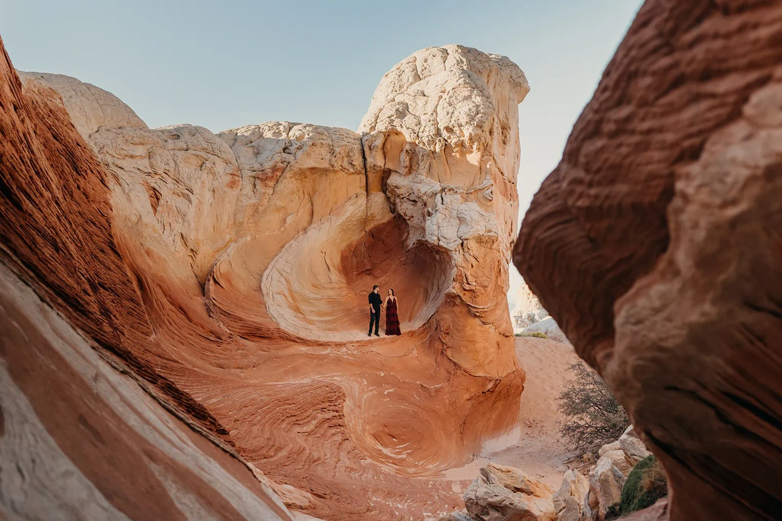 A couple stands in a colorful swirly rock formation.