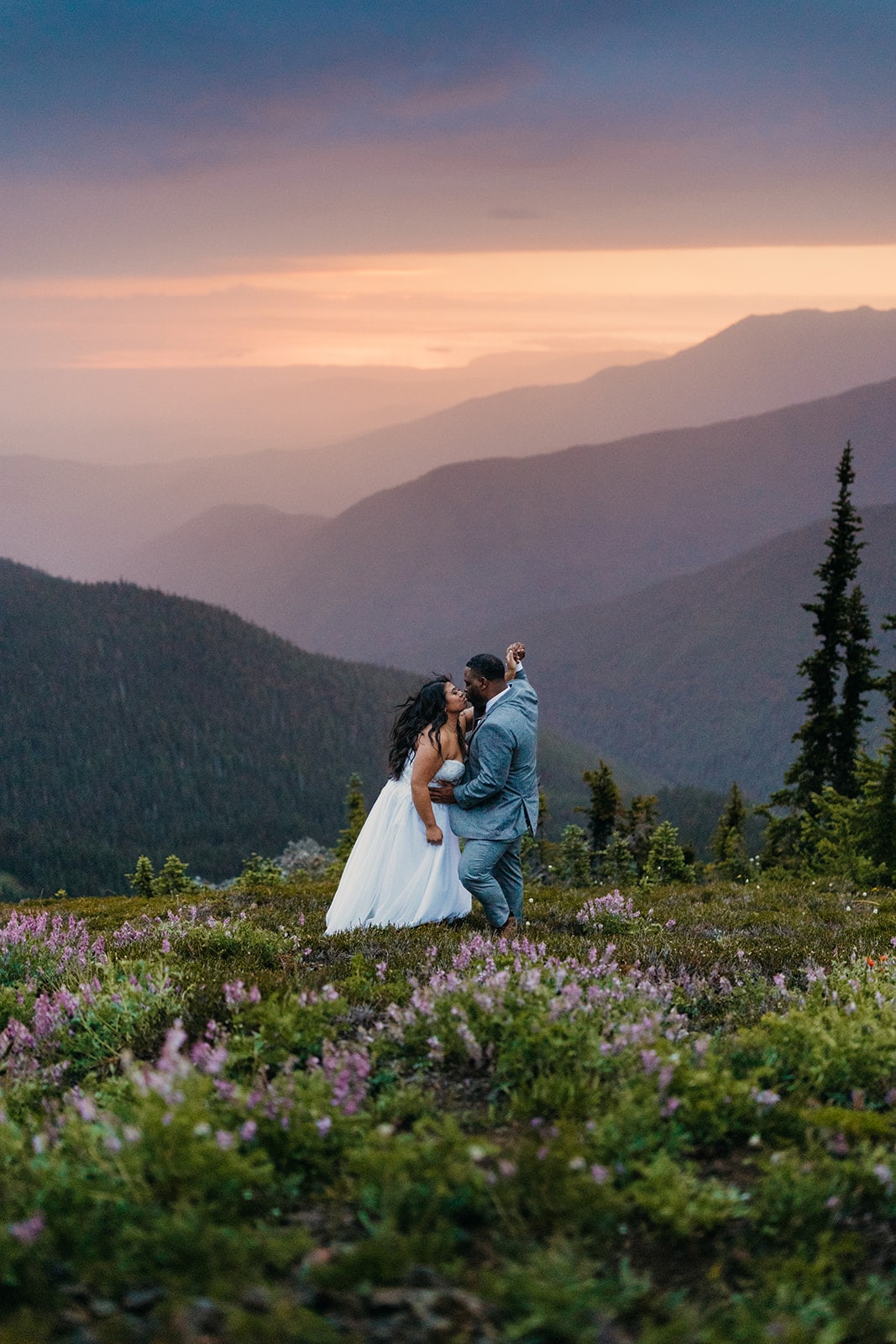 A couple shares a kiss at sunrise int he mountains on a summer day in Washington.