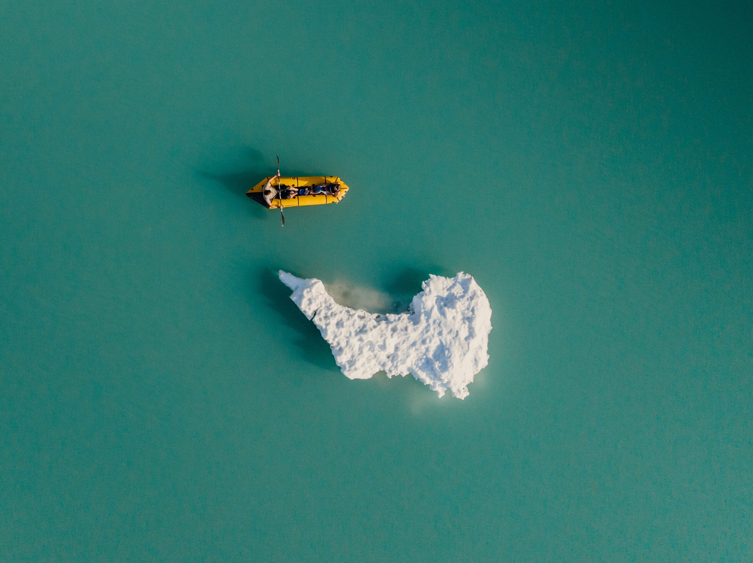 A couple floats around a glacier in their packraft.