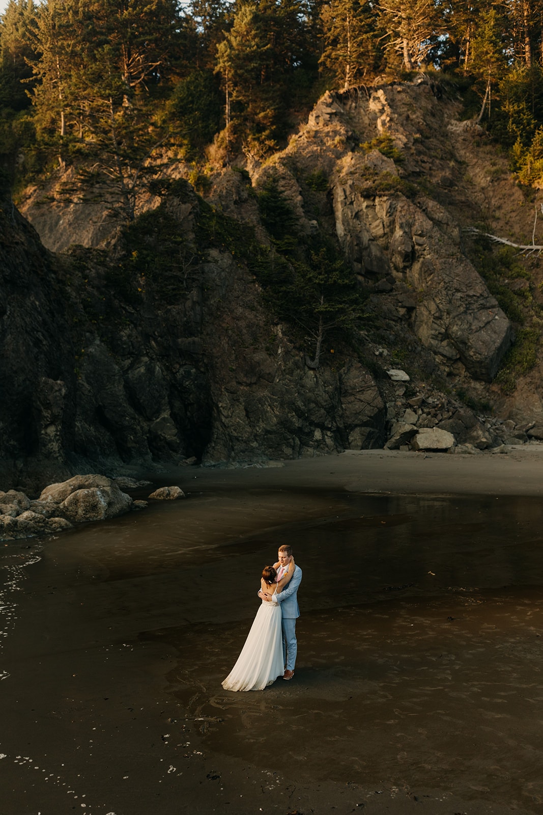 A couple dances in the sand on the coast at sunset.