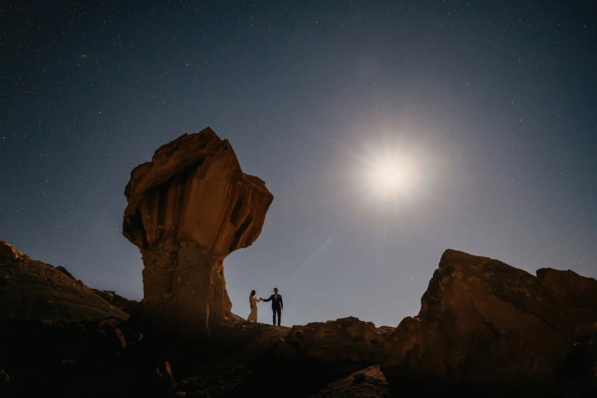 A couple walks under the moonlight.