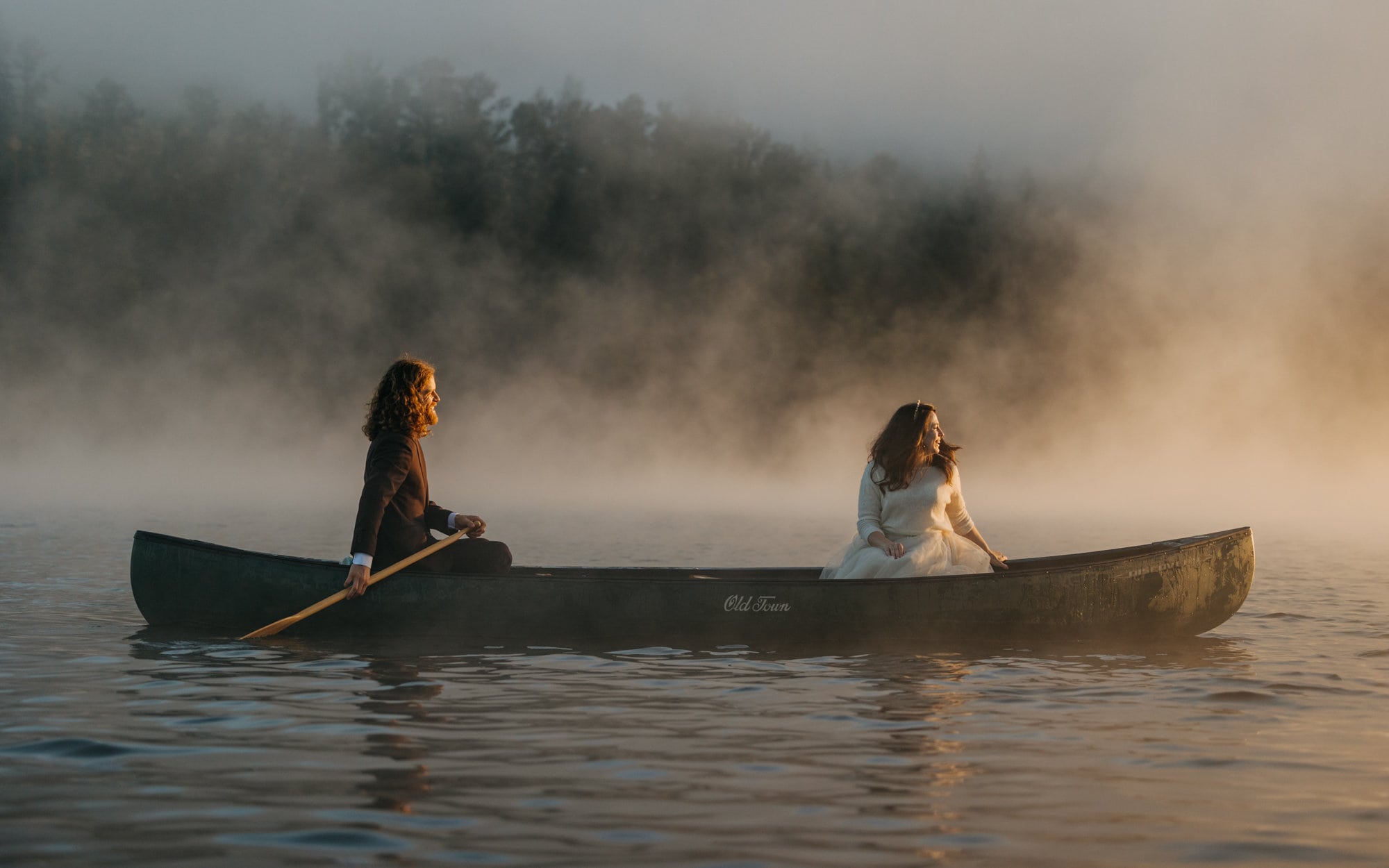 A couple canoes as the sun rises on a misty lake in Washington.