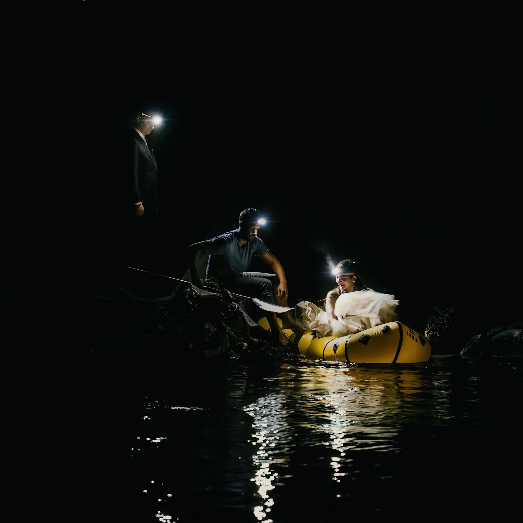 A bride sits in a packraft at night. 