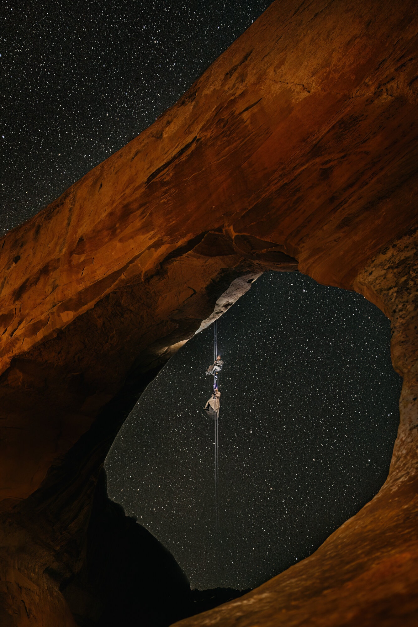 A couple rappels from an arch in the night. 