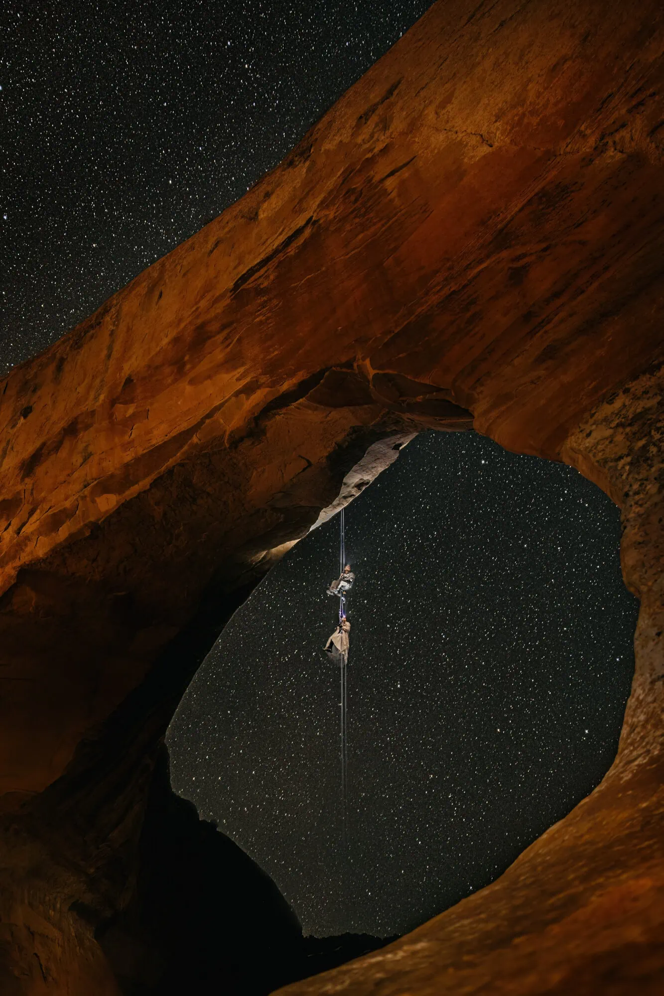 A couple rappels from an arch in the night. 