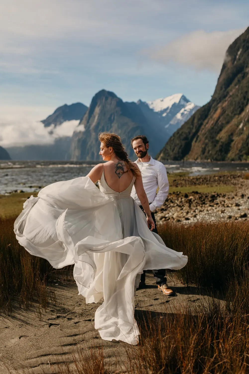 A couple poses for a photo on a windy day in Milford Sound.