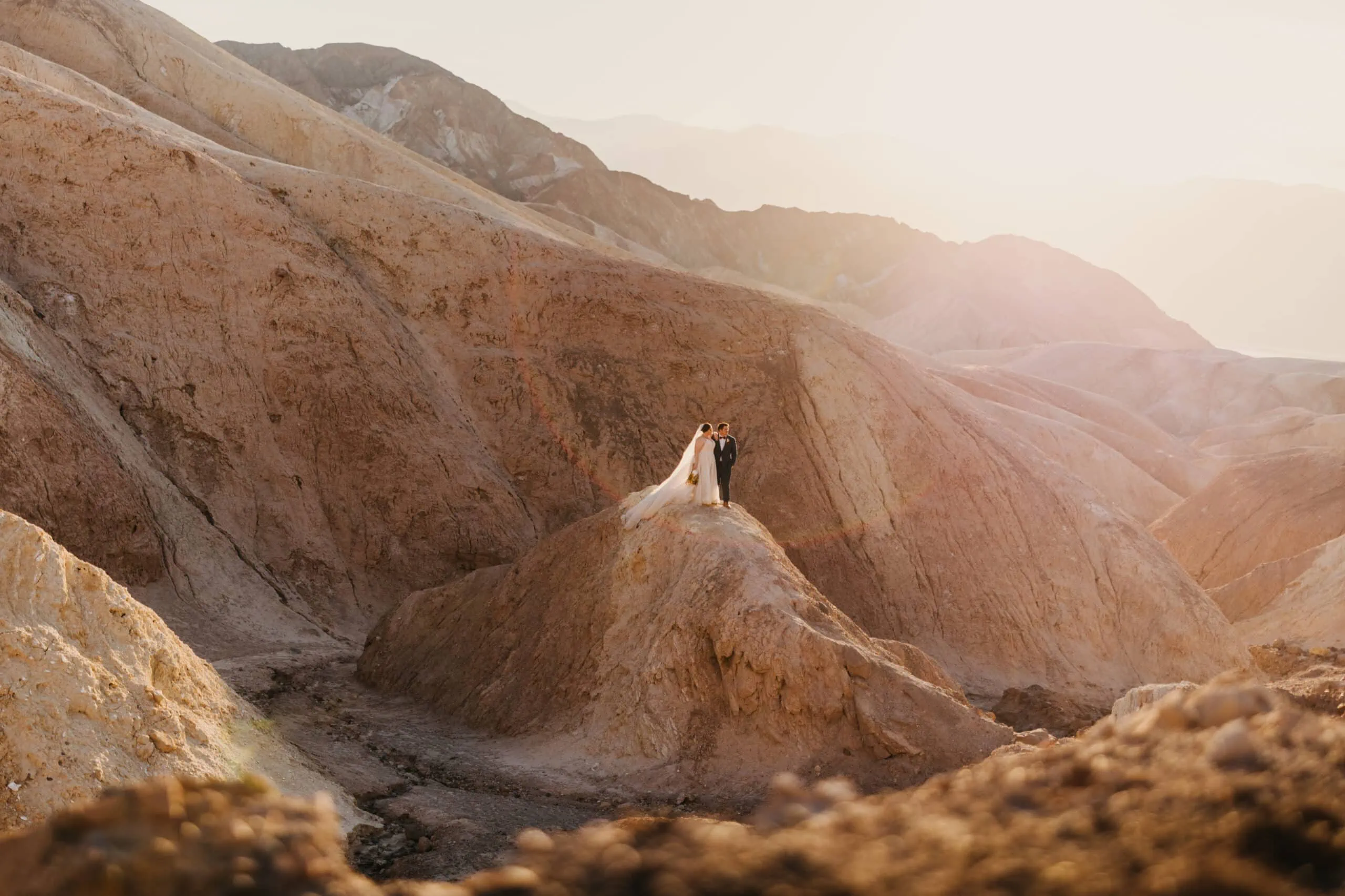 A couple stands in the sunlight in death valley for a portrait on their elopement day.