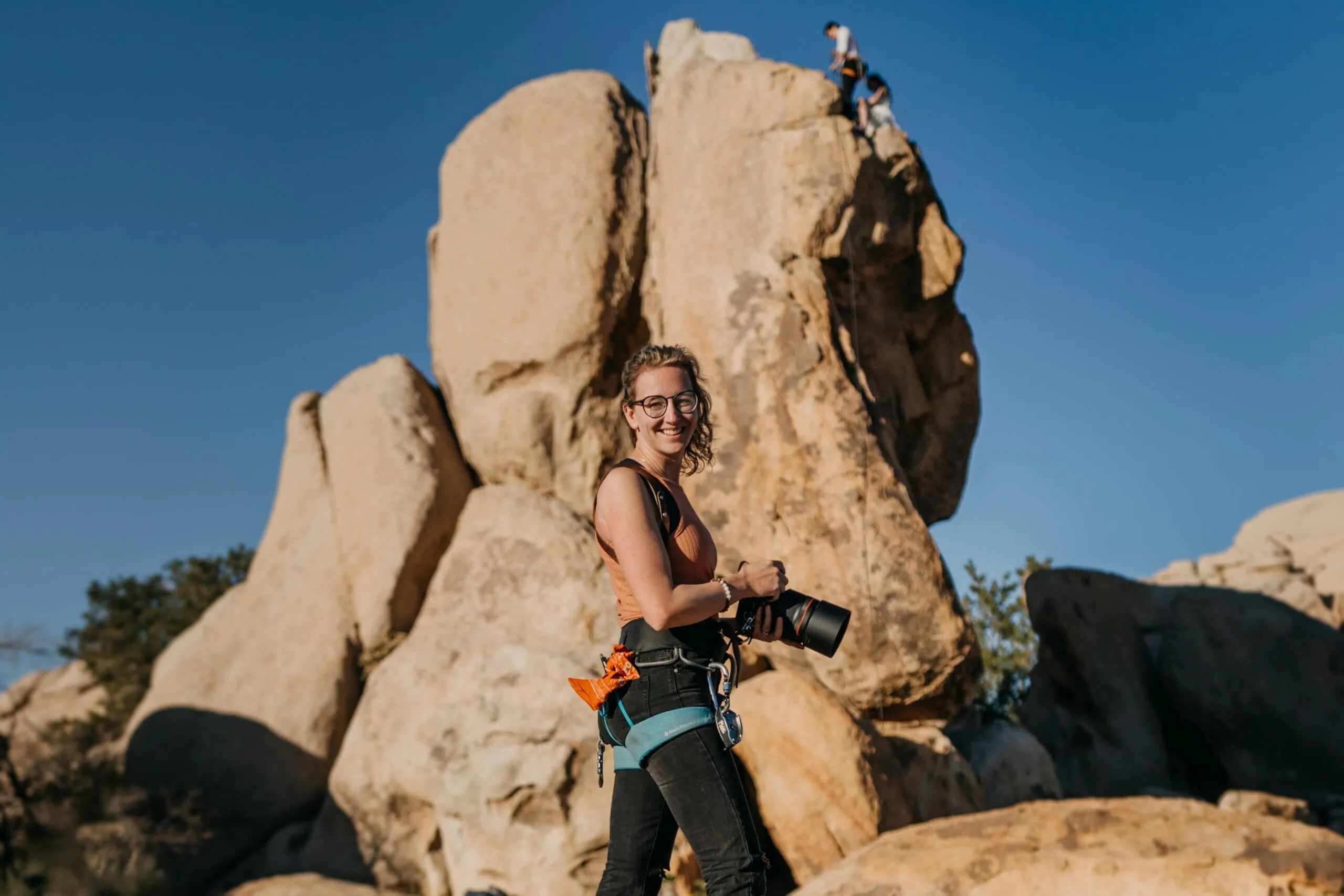 A photographer photographs a couple rock climbing.