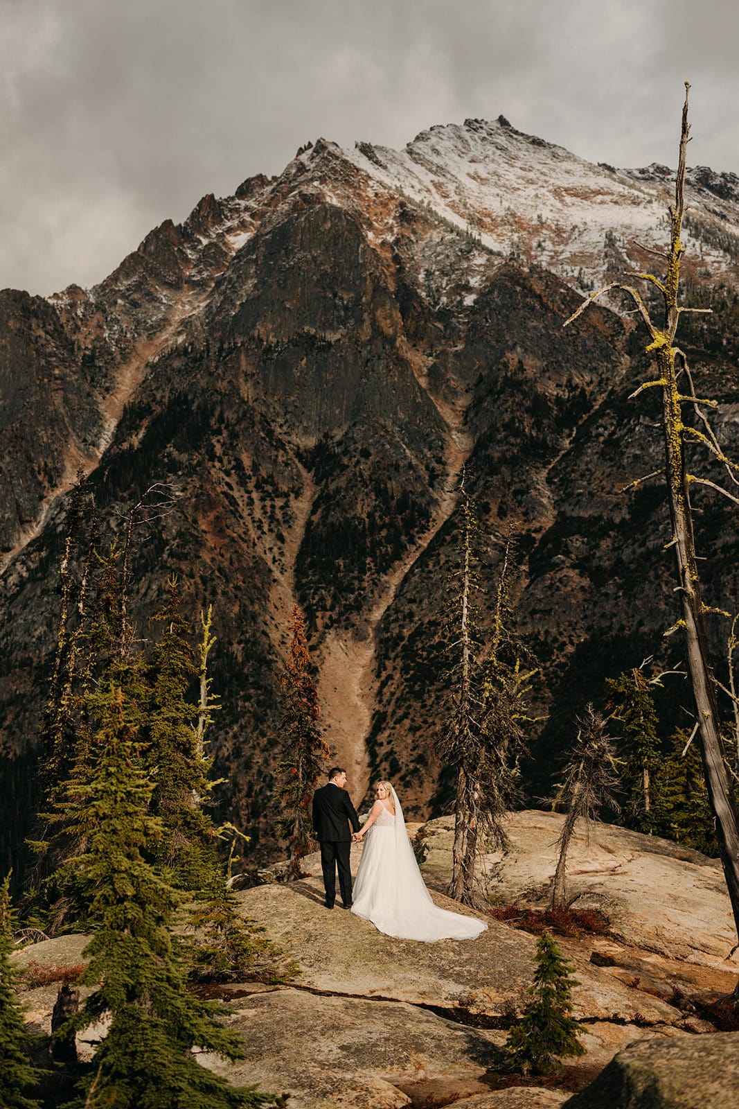 A couple walks around the Cascade Pass overlook on their wedding day after fresh snow lays on the peaks.