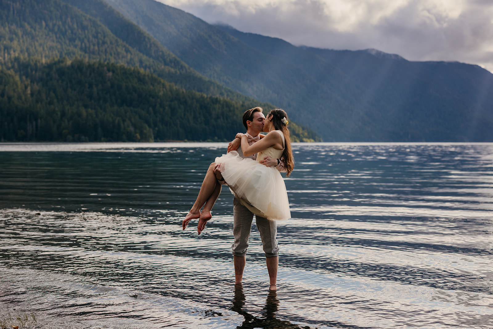 A bride wears a short elopement dress so she can plan in the lake on a summer day.