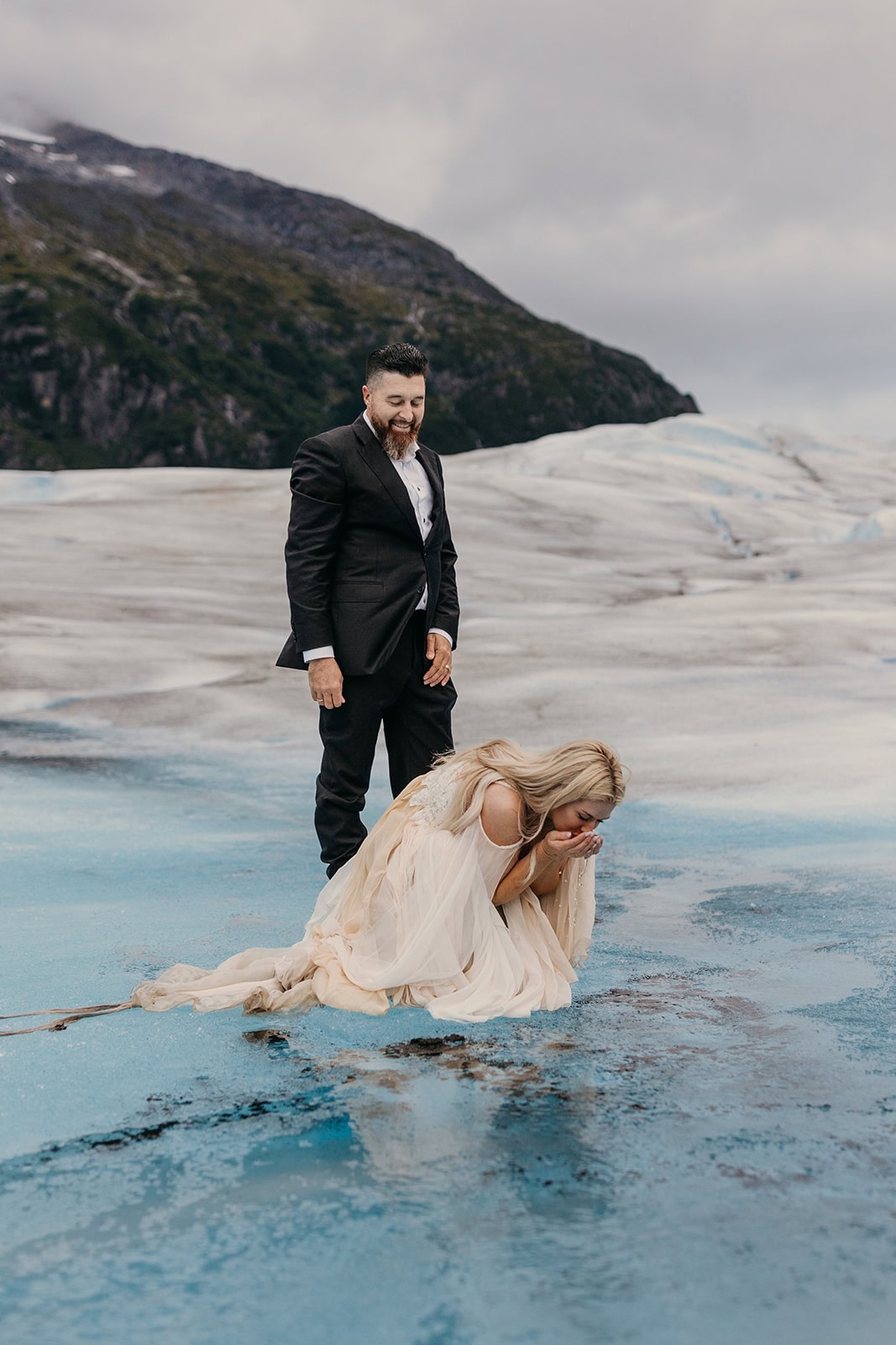A bride drinks water right off of the glacier.