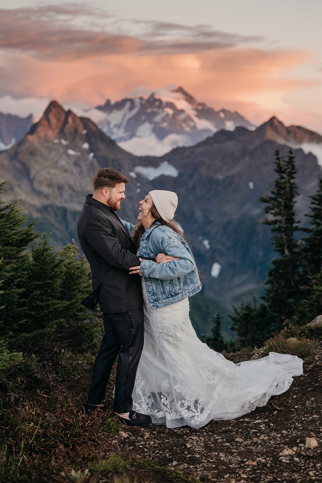 A couple holds each other while laughing in pure bliss in the mountains at sunset. 
