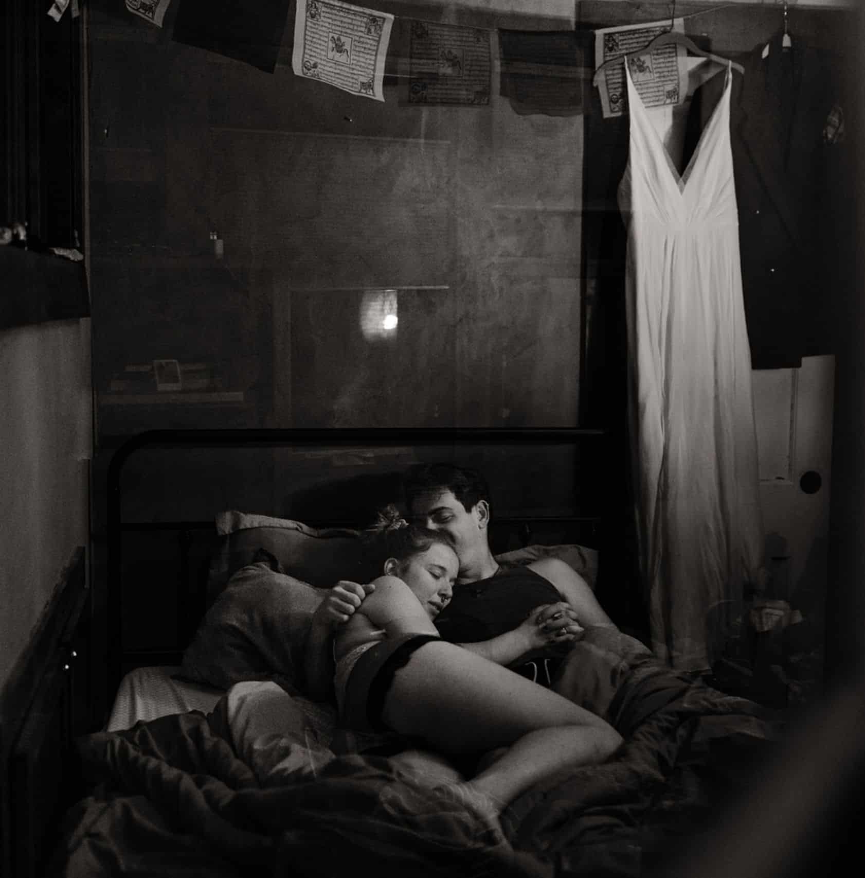 A couple curled up into each other in a bed